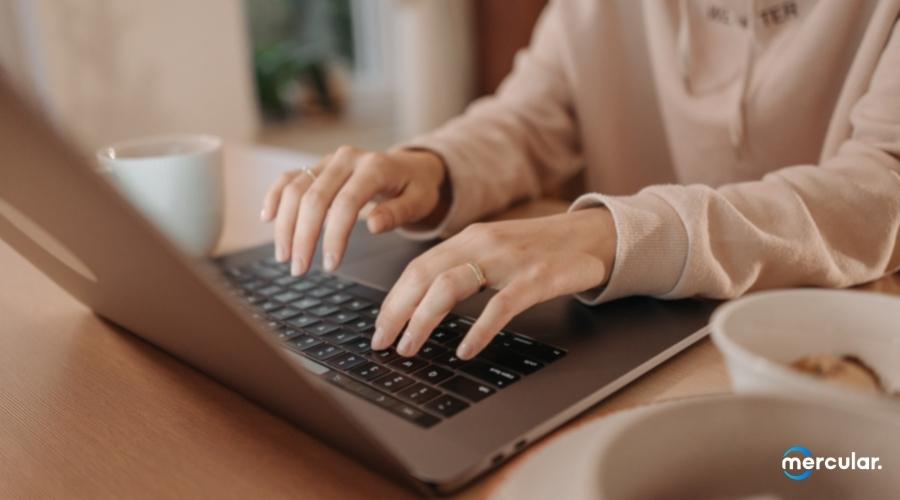 Both hand typing laptop macbook side back view